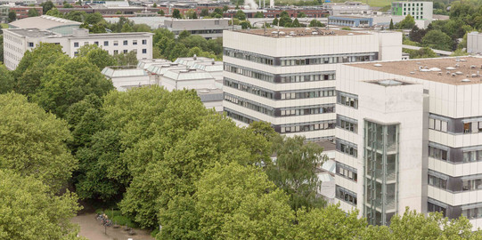 BCI-Gebäude BCI: Rechts im Bild befinden sich zwei hohe graue Gebäude mit vielen Fenstern der Fakultät Bio- und Chemieingenieurwesen. Davor und weiter links im Bild Bäume.